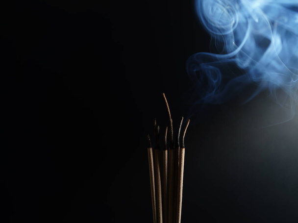 Burning incense white smoke black background used as a worship background image a sacred object of Buddhist beliefs focuses on the smoke. - Photo, image
