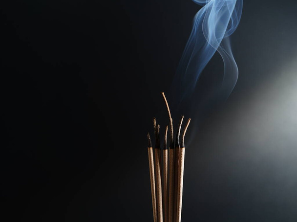 Brûler de l'encens fumée blanche fond noir utilisé comme image de fond de culte un objet sacré des croyances bouddhistes se concentre sur la fumée. - Photo, image