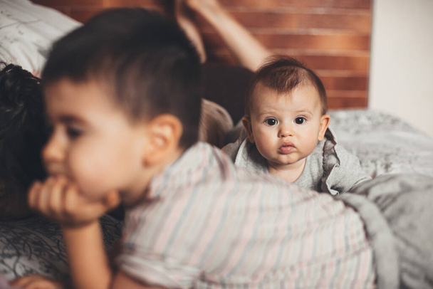Caucásico familia acostada en el sofá pasar tiempo juntos mientras recién nacido bebé está mirando a la cámara - Foto, imagen