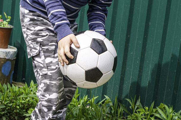 uma criança com uma bola jogando futebol no quintal - Foto, Imagem