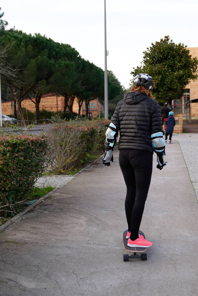 jong meisje achteraanzicht van achter vrouw rijdt een skateboard stad concept van sport lifestyle en straat cultuur - Foto, afbeelding