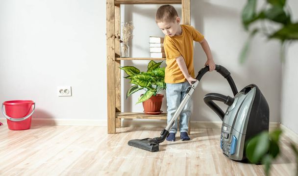 Küçük bir çocuk anne ve babasına ev işlerinde yardım ediyor, yerleri süpürgeyle temizliyor. - Fotoğraf, Görsel