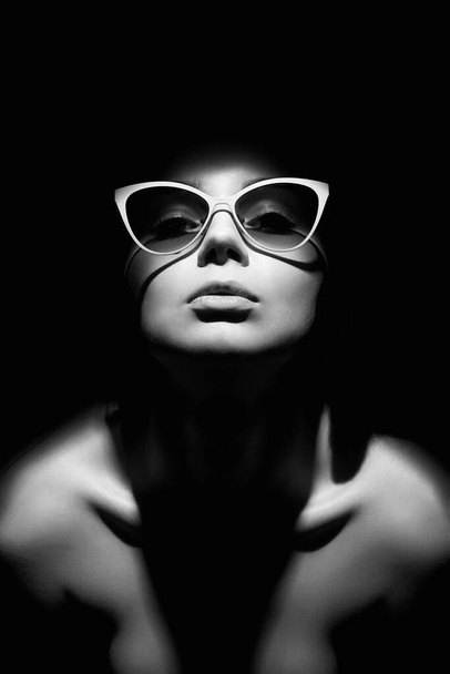 портрет красивой женщины в очках. Девушка, смотрящая из темноты - Фото, изображение