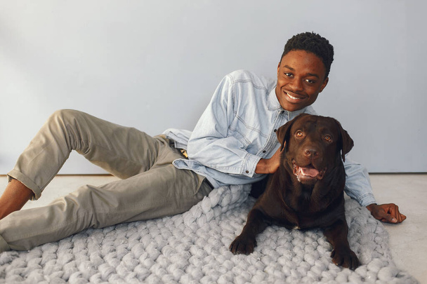 Handsome black man sitting on a blue background with a dog - Fotografie, Obrázek