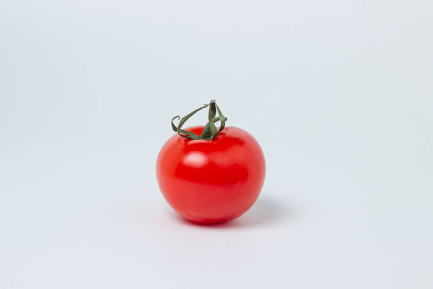 白い背景にトマトが一つ。新鮮で健康的な野菜。熟したトマトとジューシーなトマト - 写真・画像
