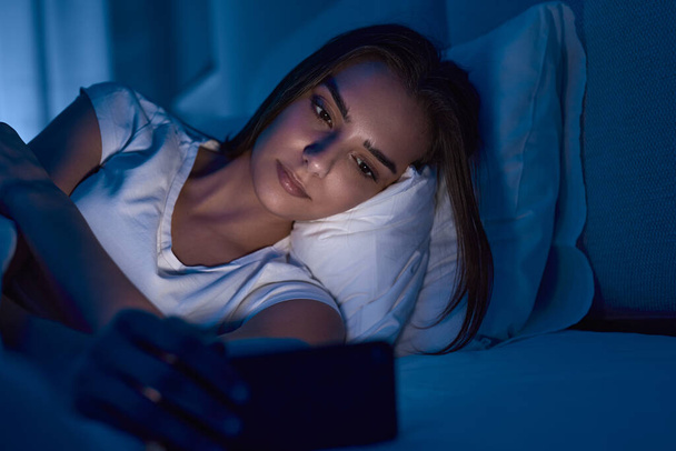 Young woman reading e book in bed - 写真・画像
