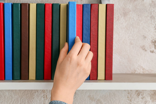 Vrouw neemt boek van plank, close-up - Foto, afbeelding