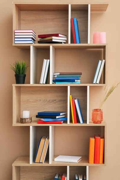 Police s knihami a výzdobou v blízkosti barevné stěny - Fotografie, Obrázek