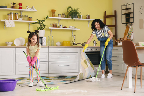 Mother and daughter mopping floor in kitchen - Photo, Image