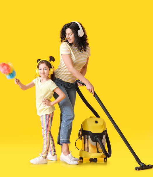 Mother and daughter with vacuum cleaner on color background - Zdjęcie, obraz