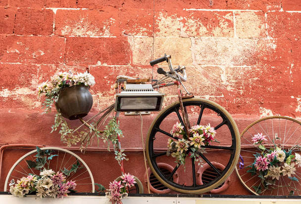 старый велосипед, как клумба висит на стене здания в Гравине в Апулии. Италия - Фото, изображение