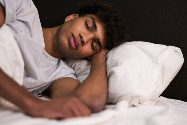 Tiefschlaf. Porträt eines friedlichen jungen Mannes, der in seinem gemütlichen Bett zu Hause schläft - Foto, Bild