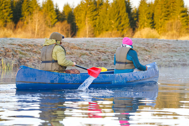 retirados remando una canoa a principios de primavera por la mañana temprano. estilo de vida de las personas mayores. Paisaje matutino, niebla junto al río matutino y gente en canoa - Foto, Imagen
