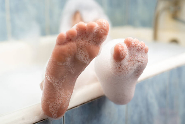 Baby feet in the foam in the bath. Hygiene, cleanliness concept. - Photo, Image