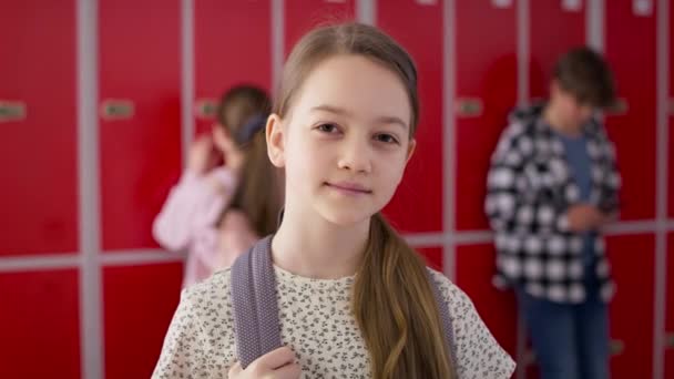 Videomuotokuva hymyilevästä tytöstä seisomassa koulussa. Laukaus punaisella heliumkameralla 8K. - Materiaali, video