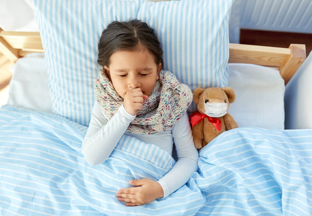 sick coughing girl with teddy bear lying in bed - Φωτογραφία, εικόνα