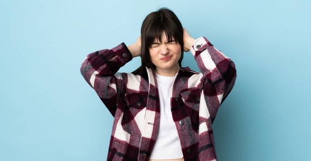 Teenager Ukrainian girl isolated on blue background frustrated and covering ears - Photo, Image