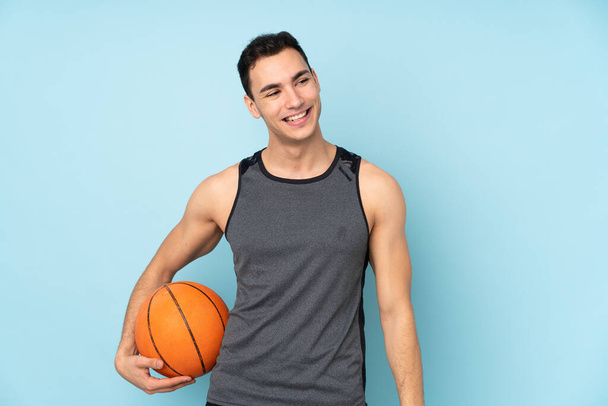 İzole edilmiş mavi arka planda basketbol oynayan adam. - Fotoğraf, Görsel