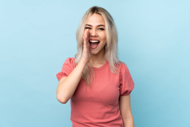 Teenager dívka přes izolované modré pozadí křičí s ústy doširoka otevřené - Fotografie, Obrázek