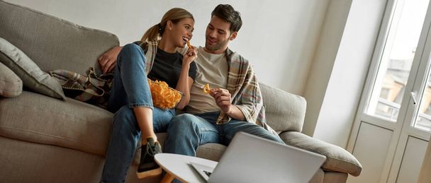 Picture of a young couple watching comedy at home and discussing jokes - Foto, Imagen