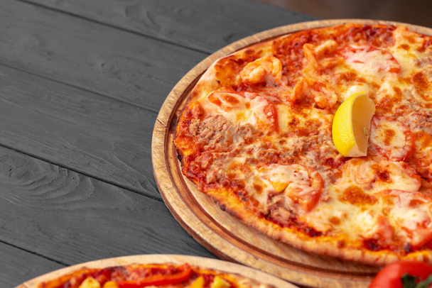 Close up of freshly baked pizza on black wooden table - 写真・画像