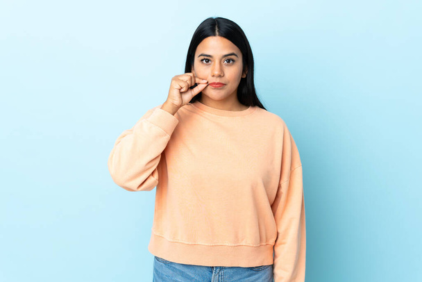 Young latin woman woman isolated on blue background showing a sign of silence gesture - Foto, Bild