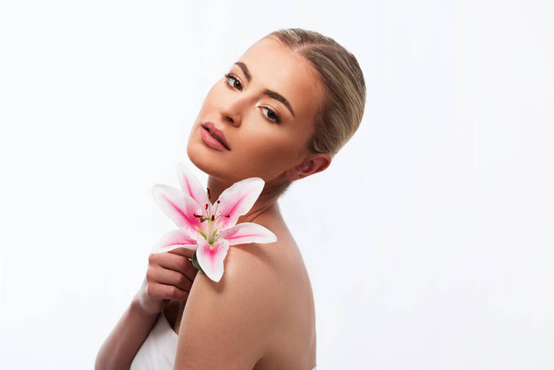 Beautiful woman holding a beautiful pink lily flower on white background  - Fotó, kép