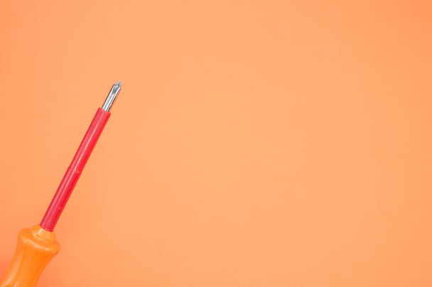 A top view of an orange screwdriver on a colorful background - Fotó, kép
