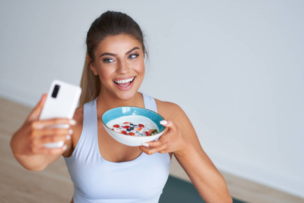 Portrét krásné hispánské ženy jíst jogurt propagující zdravý životní styl - Fotografie, Obrázek