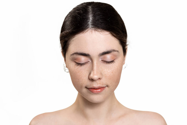 Beauty and skin care. Portrait of a young beautiful Caucasian woman with her eyes closed. Isolated on white background. The concept of cosmetology, rejuvenation and dermatology. - Fotó, kép