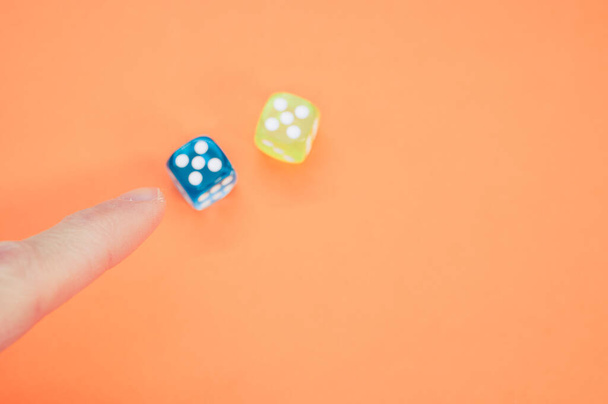 A closeup shot of a finger pointing at colored dice cubes on a colorful background - Foto, immagini