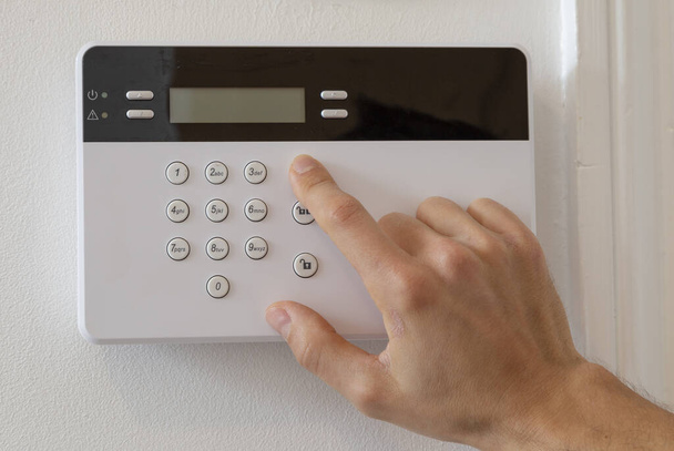A man setting up an alarm in a flat - Photo, Image