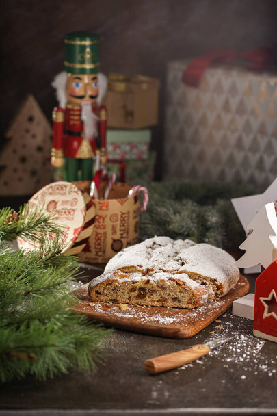 Une pâtisserie de Noël traditionnelle enflée de sucre en poudre sur une planche de bois entourée d'une décoration festive - Photo, image