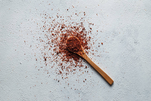 A top view of a wooden spoon and paprika on a white surfac - Foto, afbeelding