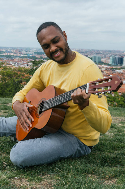 Musta mies soittaa kitaraa ulkona puistossa - Valokuva, kuva