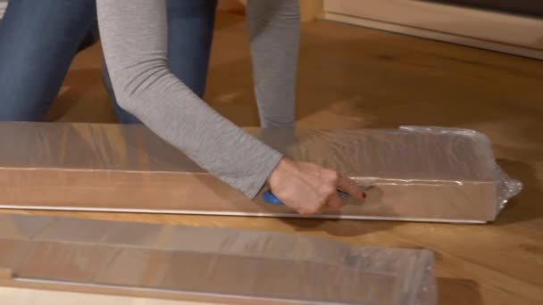 CSOPORT UP: Felismerhetetlen nő használ egy doboz vágó, hogy kibontsa darabok bútorok. - Felvétel, videó