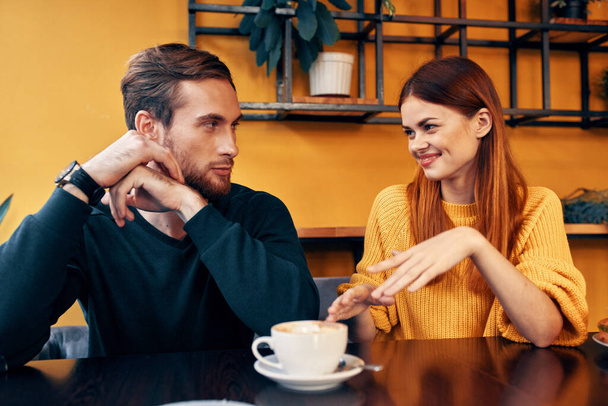 iloinen mies ja nainen elehtii käsillään ja istuu pöydässä kahvilassa viestintä ystäviä kuppi kahvia - Valokuva, kuva