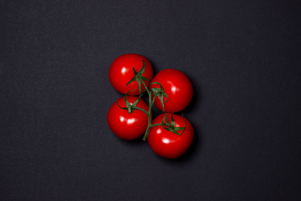 Tomatoes on a black background. Tomatoes on a vine on a dark background. Ripe fresh vegetables. - 写真・画像