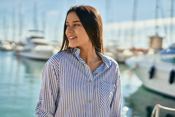 Joven chica hispana sonriendo feliz de pie en el puerto. - Foto, Imagen