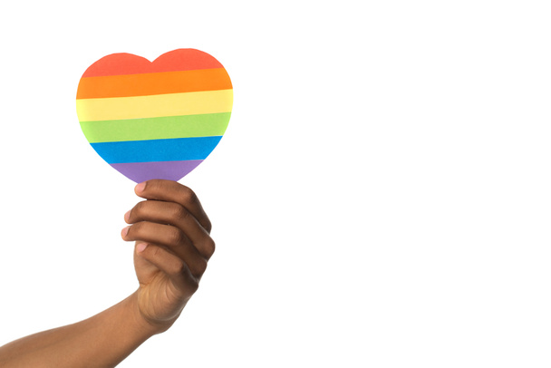 mano de africano americano celebración arco iris colores papel corazón aislado en blanco - Foto, imagen