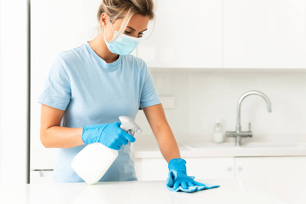 Young woman worker wearing prevention mask and gloves during apartment cleaning - Fotó, kép