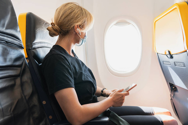 Young woman traveler wearing prevention mask during a flight inside an airplane - Φωτογραφία, εικόνα