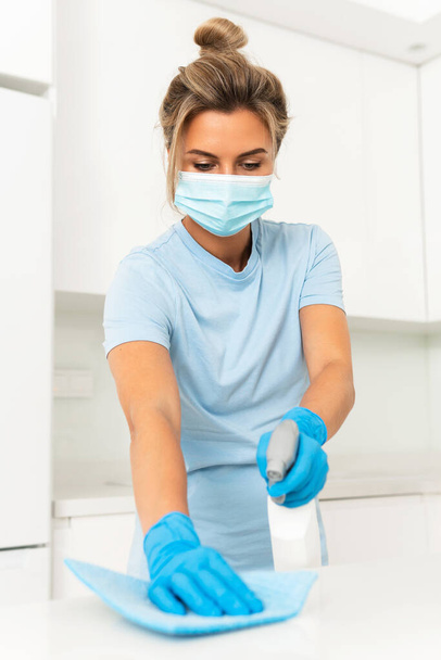 Młoda kobieta pracownik noszenia maski prewencyjnej i rękawiczki podczas sprzątania mieszkania - Zdjęcie, obraz