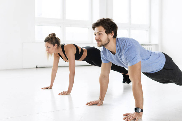Fitness man and woman during workout with in the gym. Push-ups exercise for chest and triceps muscles. - Photo, Image