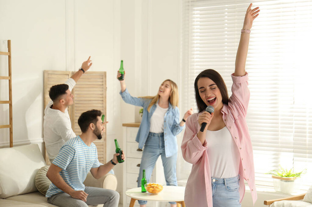 Νεαρή γυναίκα τραγουδάει καραόκε με φίλους στο σπίτι - Φωτογραφία, εικόνα