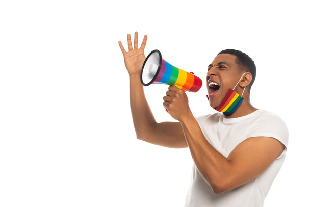 LGBT renklerinde tıbbi maskeli Afro-Amerikan bir adam hoparlörden bağırıyor. - Fotoğraf, Görsel