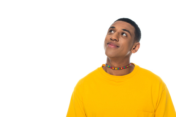 dreamy and positive african american man in rainbow colors necklace isolated on white, lgbt concept - Photo, Image