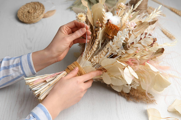 Florist making beautiful bouquet of dried flowers at white table, closeup - Foto, afbeelding