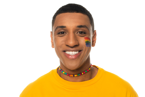 african american man with lgbt flag painted on face smiling at camera isolated on white - Фото, изображение