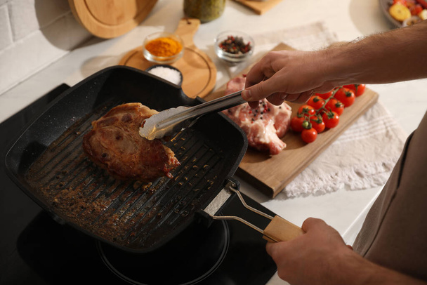 Man taking cooked tasty meat from frying pan, closeup - Foto, imagen